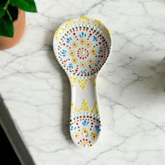 a ceramic spoon sitting on top of a white counter next to a potted plant