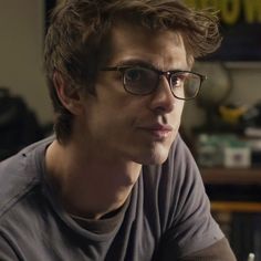 a man wearing glasses sitting in front of a desk