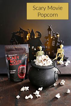 a black caulder filled with popcorn sitting on top of a table next to a bag of popcorn