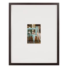 a blue chair sitting on top of a wooden floor next to a white framed wall