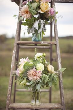 flowers are arranged in vases on an old ladder