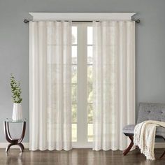 a living room with beige curtains and white furniture in the corner, along with a window curtain