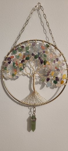 the tree of life has many different colored stones on it's branches and is hanging from a chain