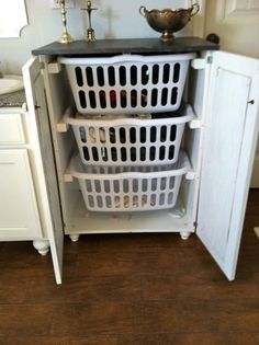 three laundry baskets stacked on top of each other in front of an open refrigerator door