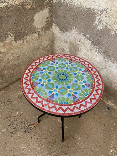 a colorful table sitting on top of a cement floor