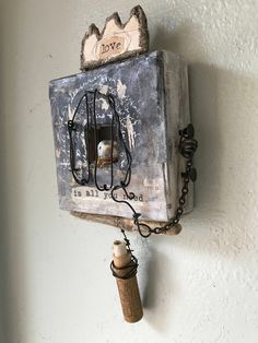 an old box with a chain hanging from it's side and a wine bottle in the middle