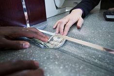 two hands reaching for money on top of a counter