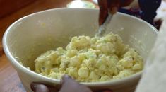 a person is stirring mashed potatoes in a bowl