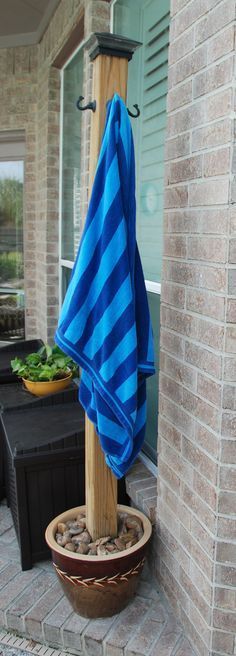 a blue and white towel is hanging on a wooden pole next to a potted plant