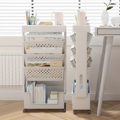 a white book shelf filled with books next to a desk and window covered in blinds