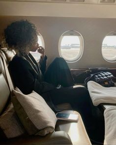 a woman sitting on an airplane seat with her feet up and looking out the window