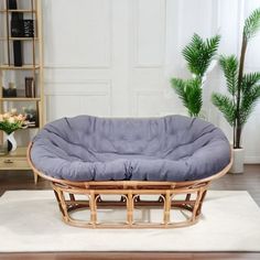 a wicker dog bed on top of a rug in a living room next to a potted plant