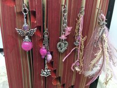 several charms are hanging from a book with pink ribbon and beads on it, along with other items