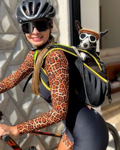 a woman with a dog on her back riding a bike wearing a leopard print outfit