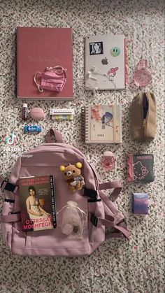 the contents of a pink backpack laid out on a floral print bed spread, including books and other items