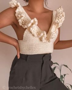 a woman is wearing a crochet top with ruffles