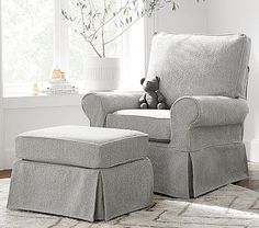 a gray chair and ottoman with a stuffed animal on it in front of a window