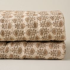 two bedspreads with brown and tan designs on them, one is folded over the other