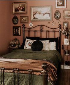 a bedroom with pink walls and pictures on the wall above the bed, along with an iron frame headboard