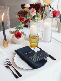 a table set with candles, flowers and menus for a wedding or special event