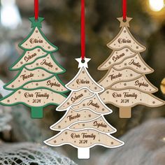 three wooden christmas tree ornaments hanging from strings