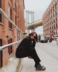 a woman sitting on the side of a building while talking on a cell phone