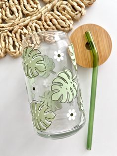 a glass cup with a green handle next to a wooden spoon and some straws