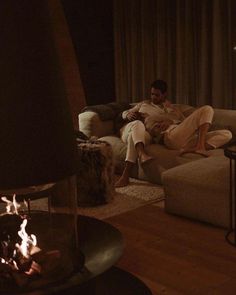 a man and woman sitting on a couch next to a fire place in a living room