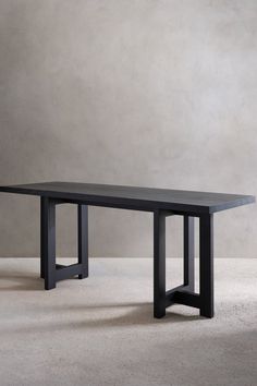 a black table sitting on top of a white floor next to a gray wall in an empty room