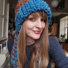 a woman with long hair wearing a blue and orange knitted hat in a kitchen