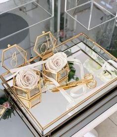 two roses are sitting on top of a mirrored tray with gold trimmings and letters