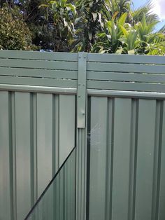 a dog is standing in front of a green fence