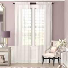 a living room with purple walls and white curtains