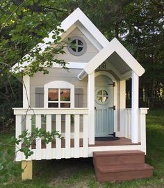 a small white house sitting on top of a lush green field next to a tree