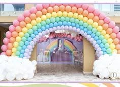 an arch made out of balloons in the shape of a rainbow with clouds on it