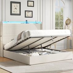 a white bed with a pull out mattress and storage underneath it in a living room