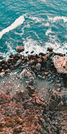 an aerial view of the ocean and rocks