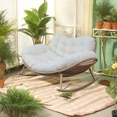 a white futon chair sitting on top of a rug next to potted plants