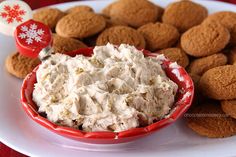 a red bowl filled with cream cheese next to crackers on a white and red plate