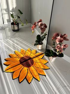 a sunflower rug sitting on top of a white counter next to potted plants