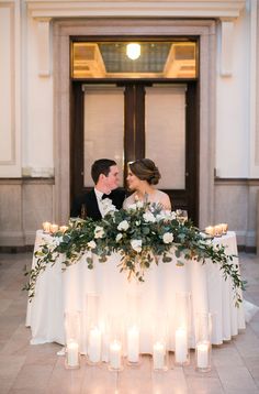 a bride and groom sitting at a table with candles