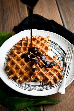 a white plate topped with waffles covered in syrup