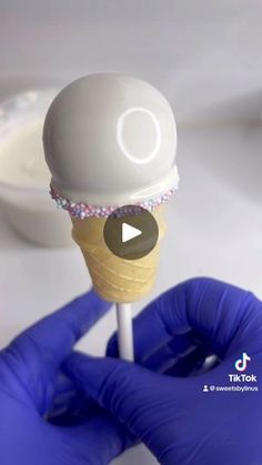 an ice cream cone is being held up by someone's hand with blue gloves