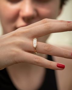 a woman wearing a gold ring with a diamond on it's middle finger and red nails