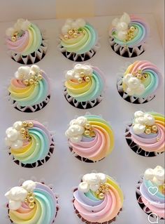 the cupcakes are decorated with rainbow icing and white flowers on them,