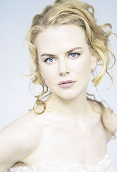 a woman with blonde hair and blue eyes wearing a white dress is looking at the camera