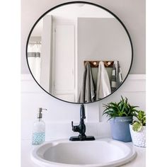 a bathroom sink with a round mirror above it