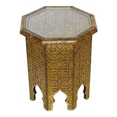 a gold and glass side table with an intricate design