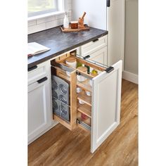 an open cabinet in the middle of a kitchen with white cabinets and wood flooring