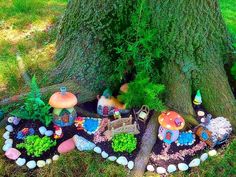 a group of gnomes are sitting in the grass near a tree and some rocks